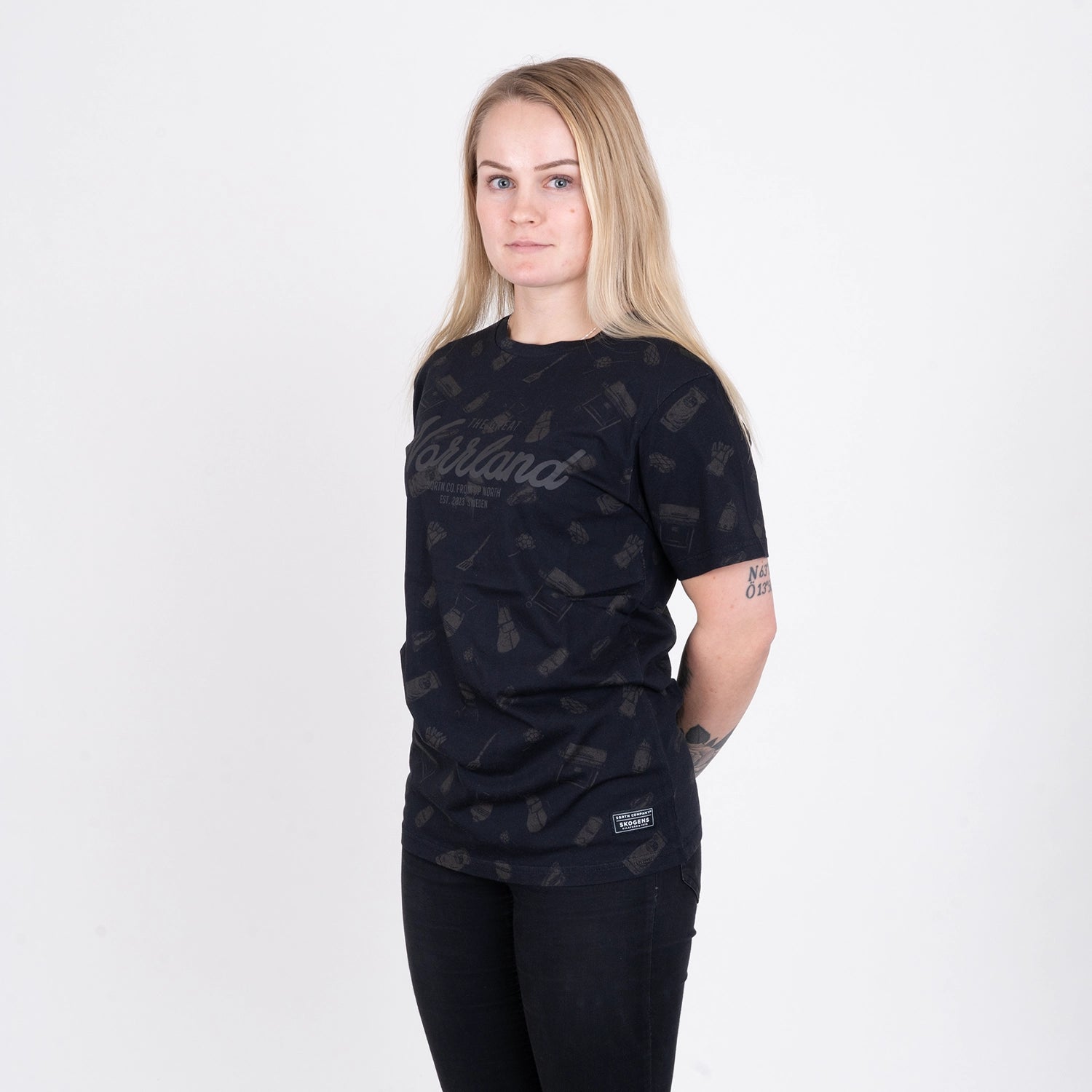Kvinna i svart t-shirt med grillmotiv och subtil Norrländ-design mot vit bakgrund