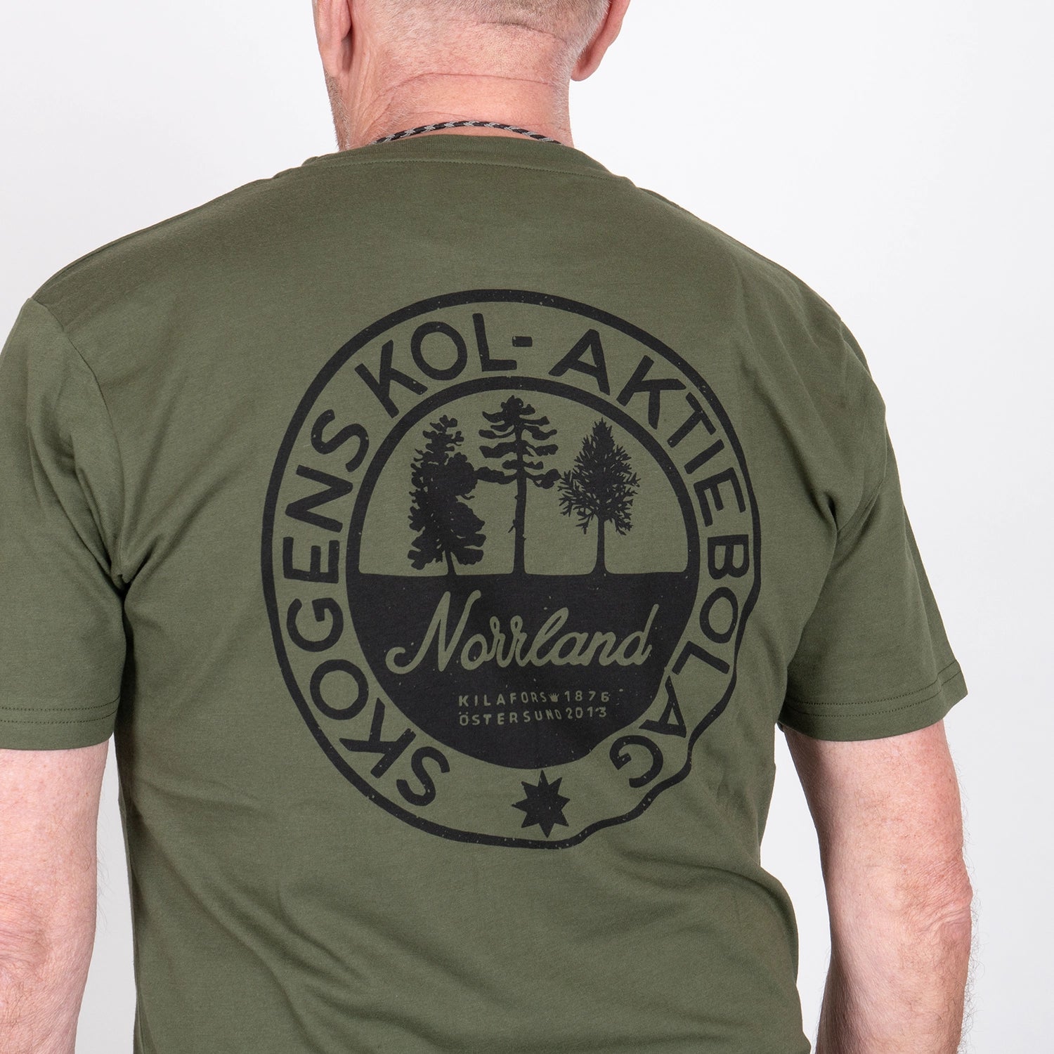 Olivgrön t-shirt med stor rund Norrland-logga och trädgrafik på ryggen, herrmodell.