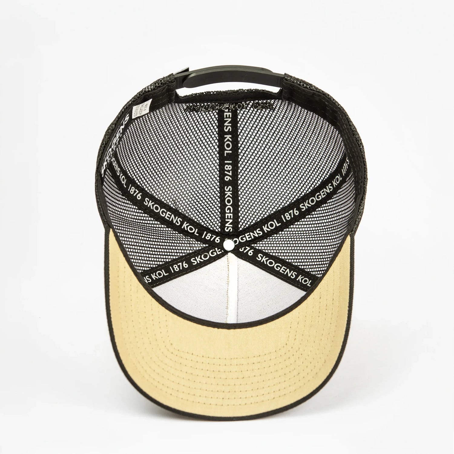 Baksida av svart och beige keps med nätpanel och texten 'SKOGENS KOL 1876' på insidan.
