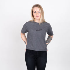 Kvinna i grå t-shirt med texten 'Skogens', grillkläder, enkel vit bakgrund