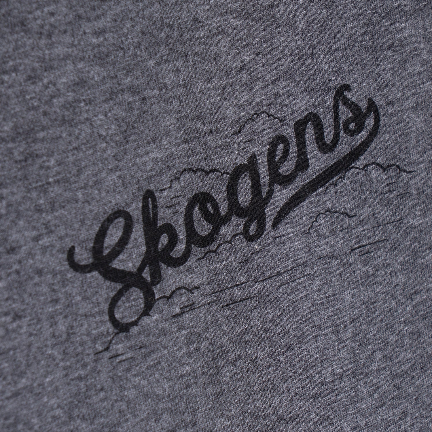 Närbild av grå t-shirt med svart tryck och texten 'Skogens', grillkläder accessoar