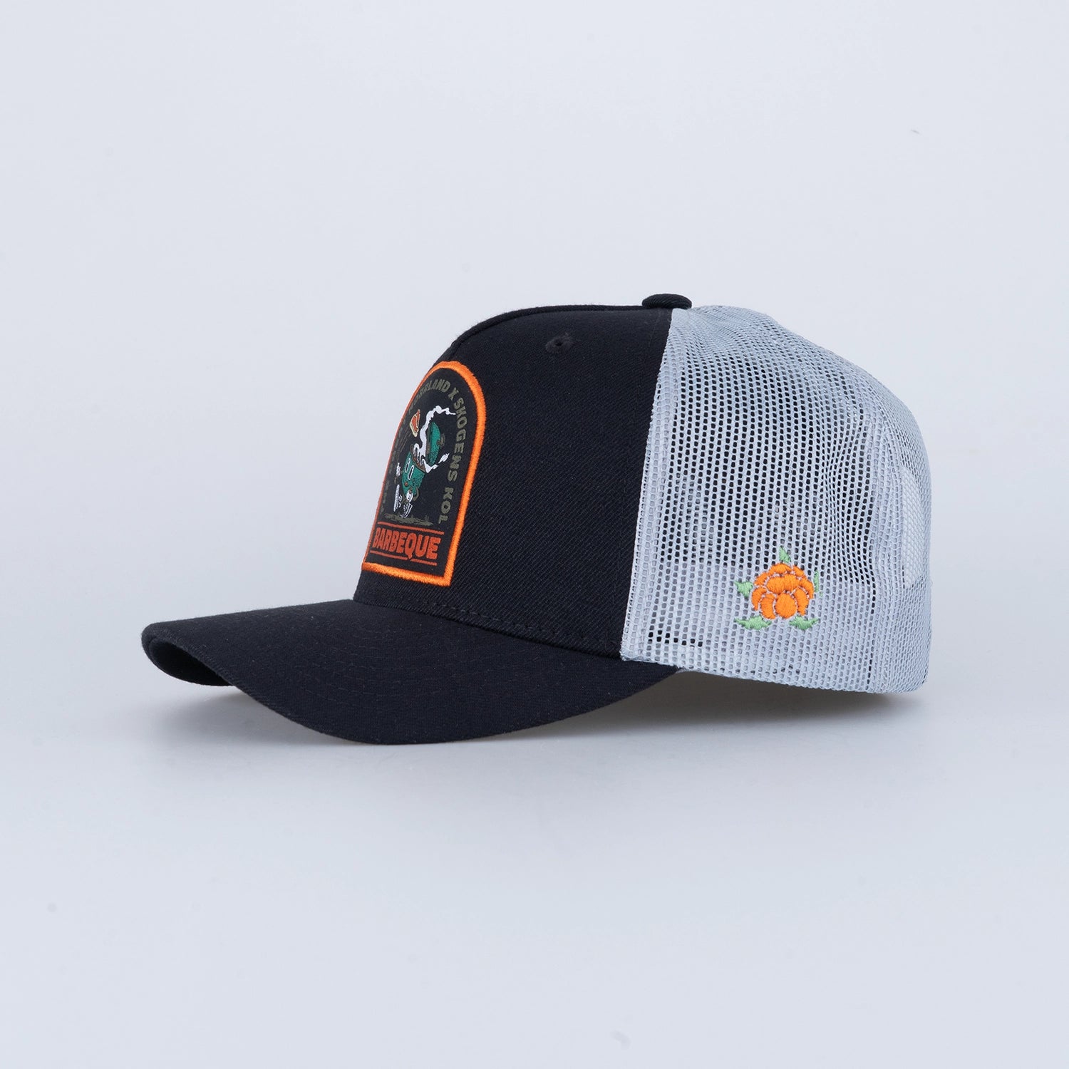 Svart och vit truckerkeps med grillmotiv, broderad patch och nätpanel, barbeque-keps.
