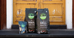 Tre påsar grillkol, grillbriketter och träull utanför en gul dörr, perfekta för grillning.