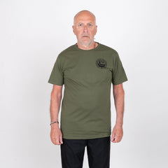 Man i olivgrön t-shirt med svart tryck, neutralt poserande mot vit bakgrund.