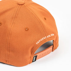 Orange keps med justerbar rem och texten SKOGENS KOL 1876, grilltillbehörsdesign.