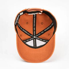 Orange keps med svart textband 'SKOGENS KOL 1876' på insidan, liggande på vit bakgrund.