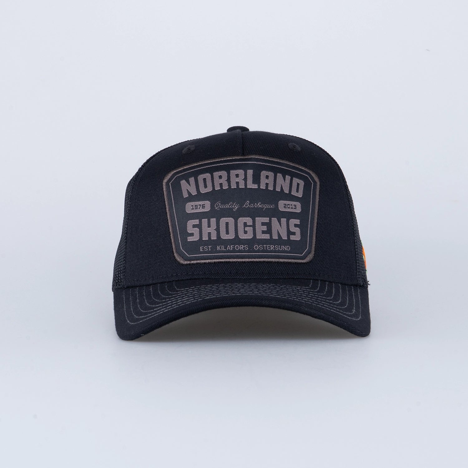 Svart truckerkeps med patch och texten NORRLAND SKOGENS, Kilafors och Östersund.